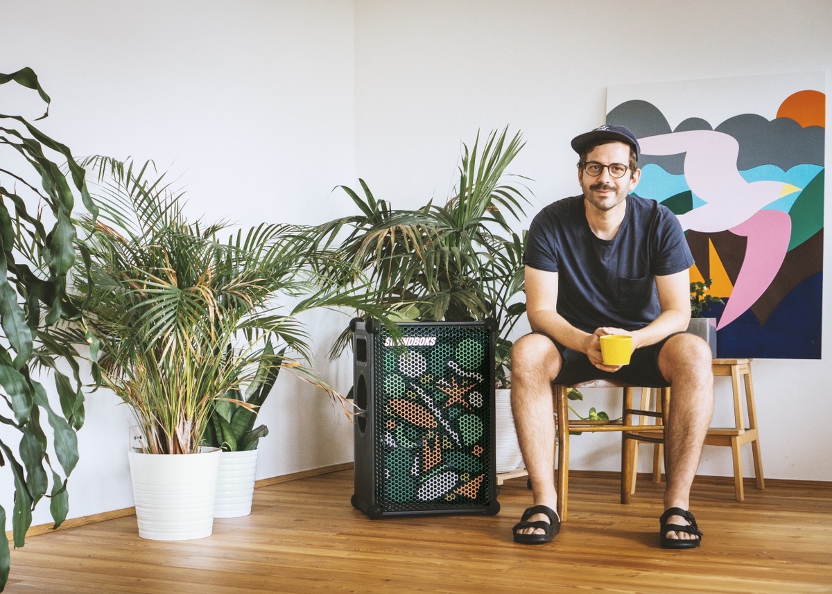  man sitting on a chair with a coffee cup next to a limited edition artist grill soundboks