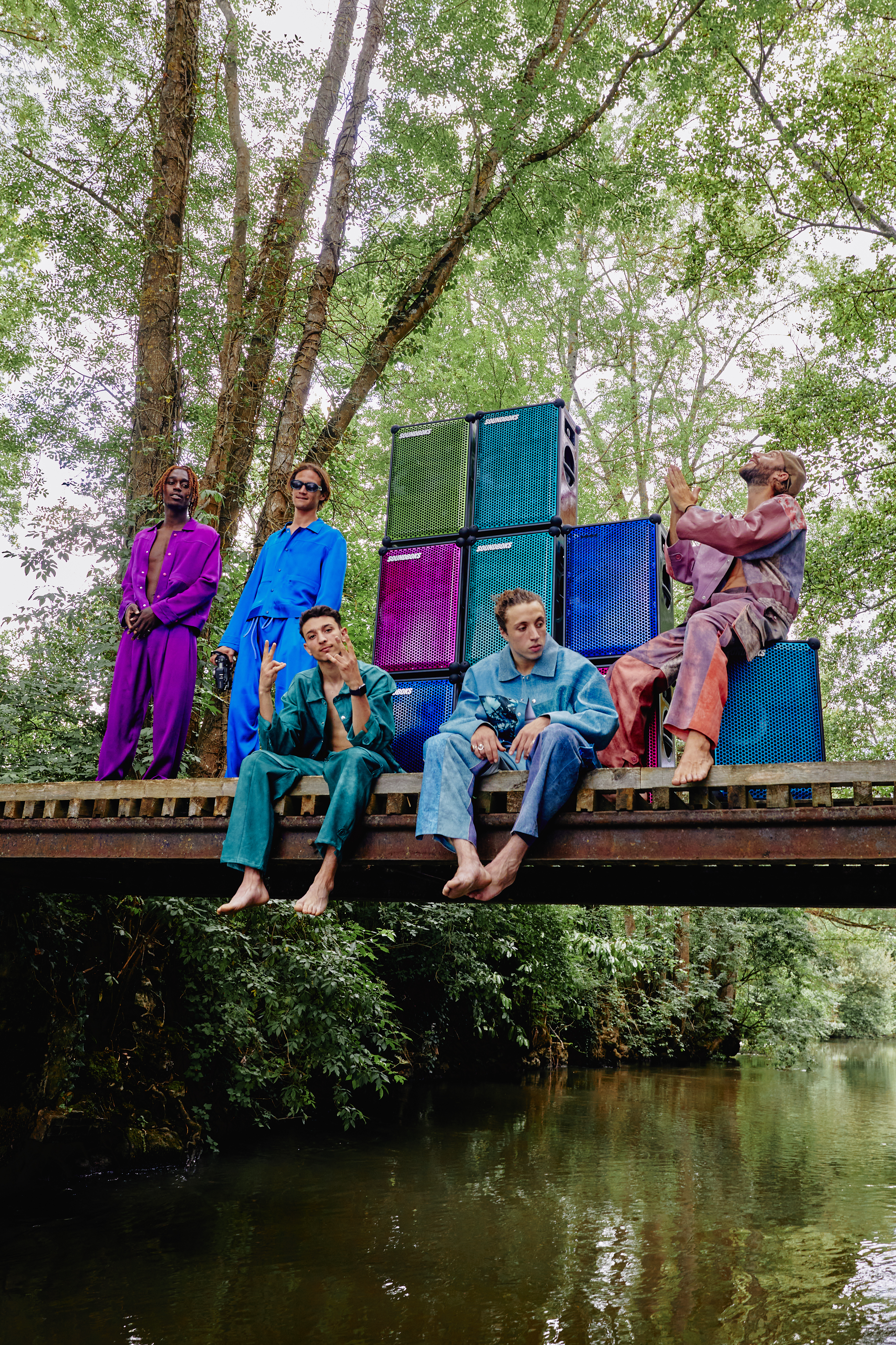 people sitting on a bridge with a bunch of speakers in various colors