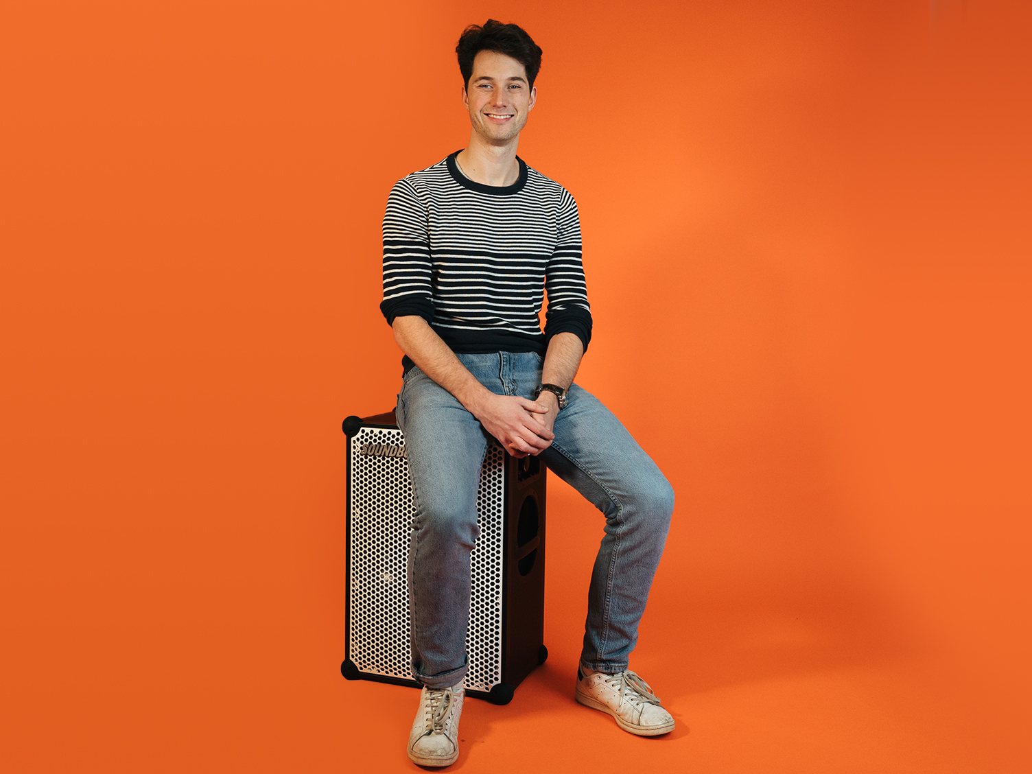 Wouter, digital director at soundboks sitting on a soundboks in front of an orange background