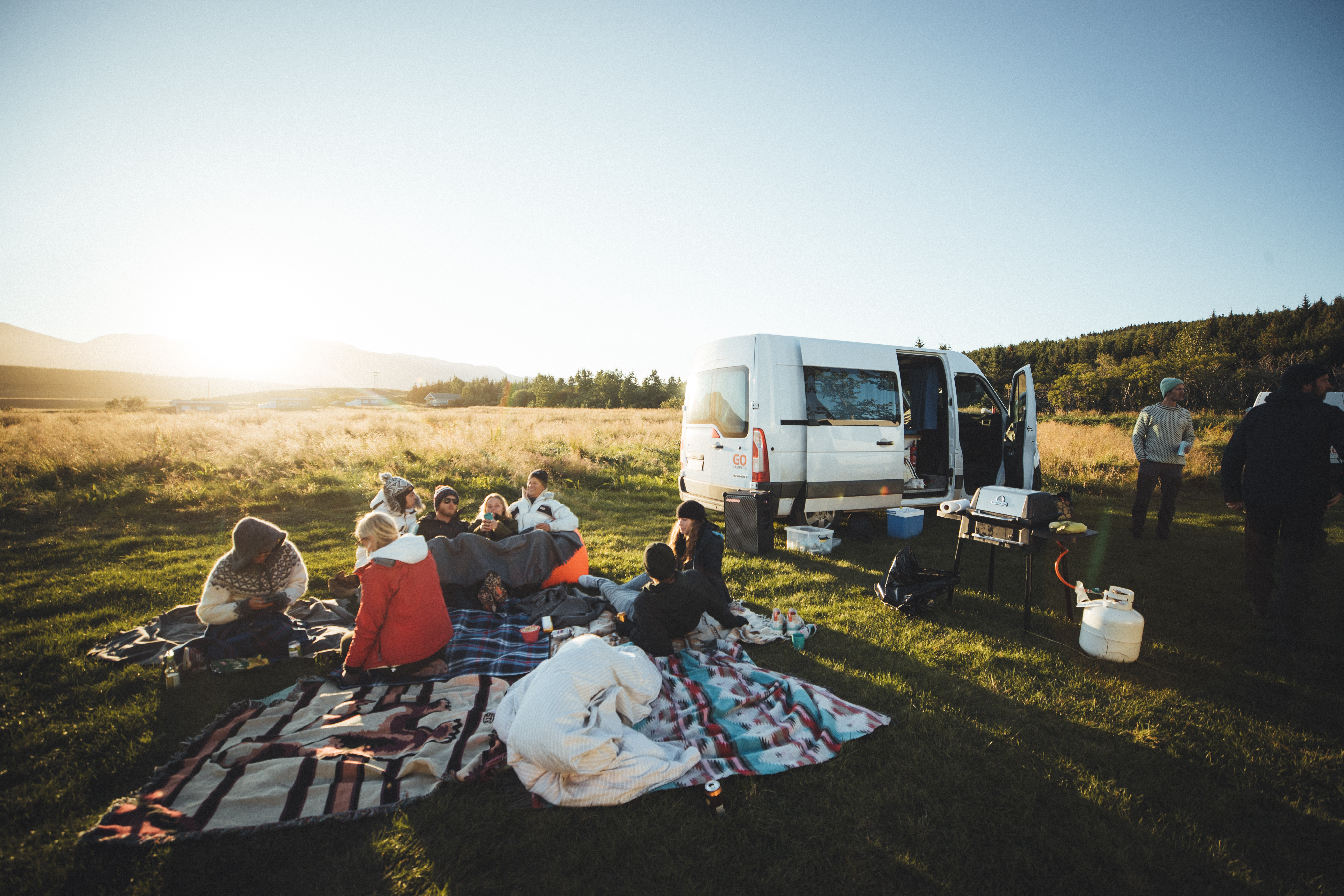 people having a picnic in front of a white sprinter van with a soundboks listening to music