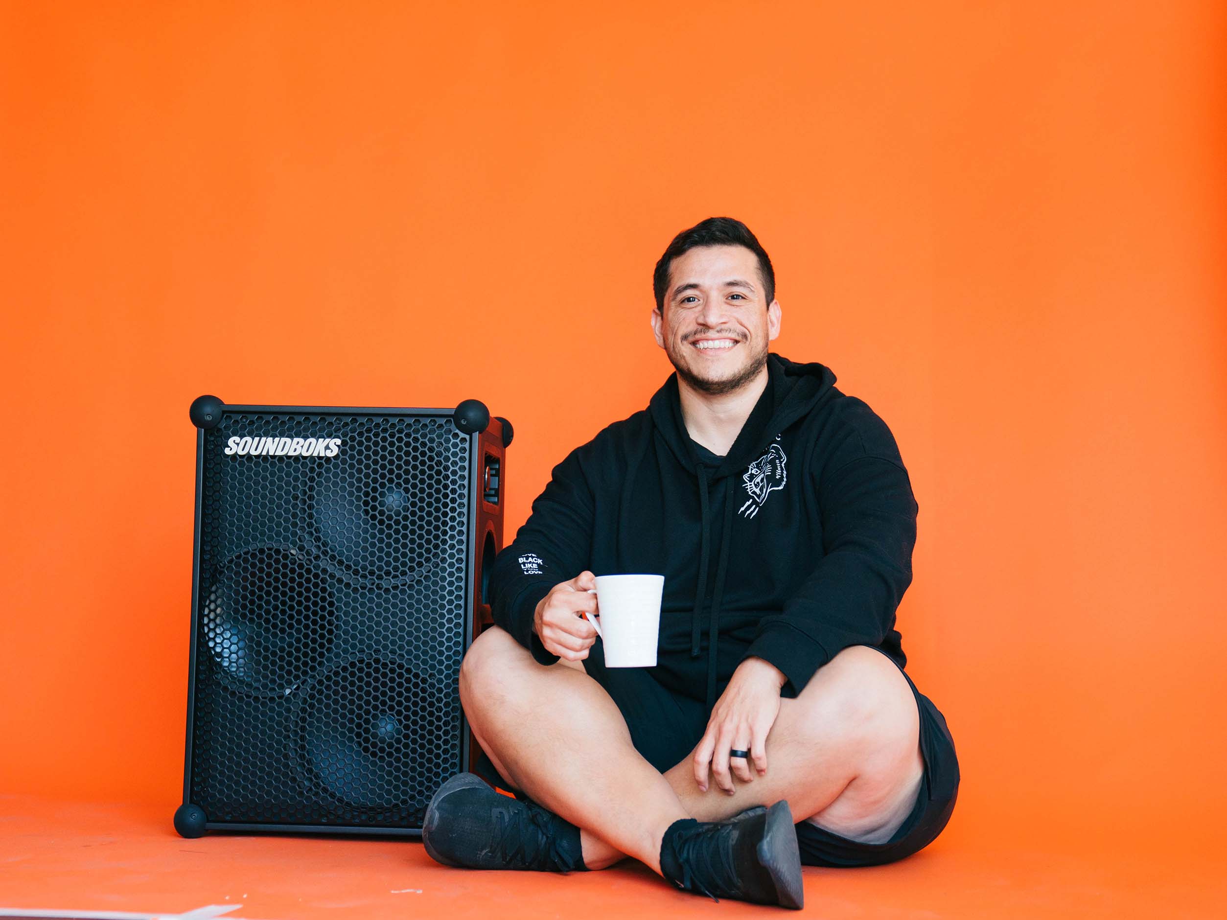 Matthew drinking a cup of coffee next to a SOUNDBOKS speaker