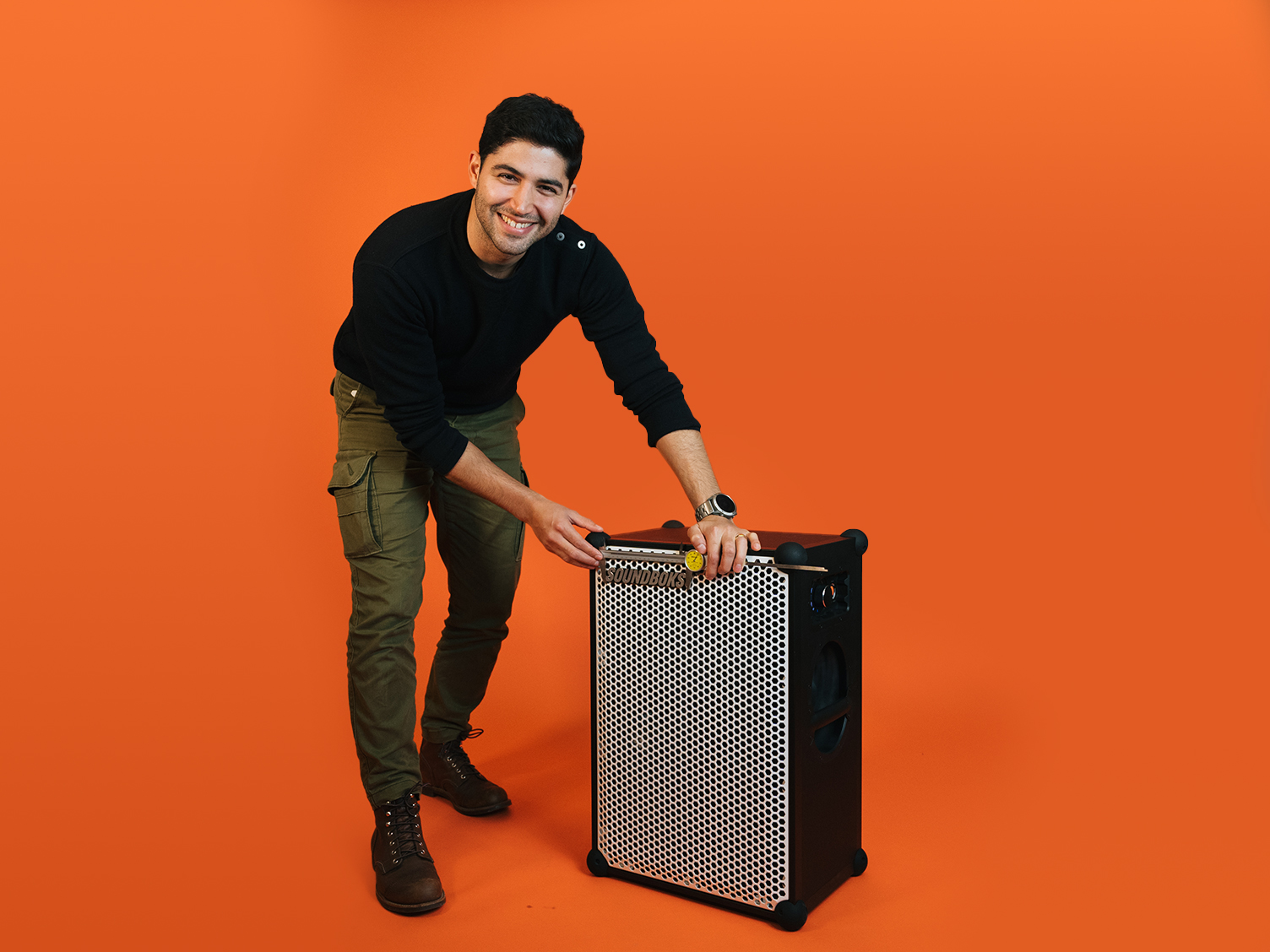 Amir, mechanical engineer measuring a SOUNDBOKS in front of an orange background