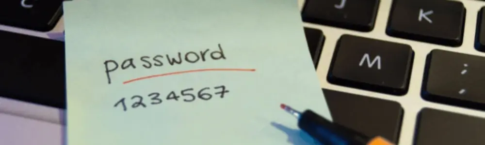 the words password and 1234567 are written in pen on a green sticky-note resting computer keyboard