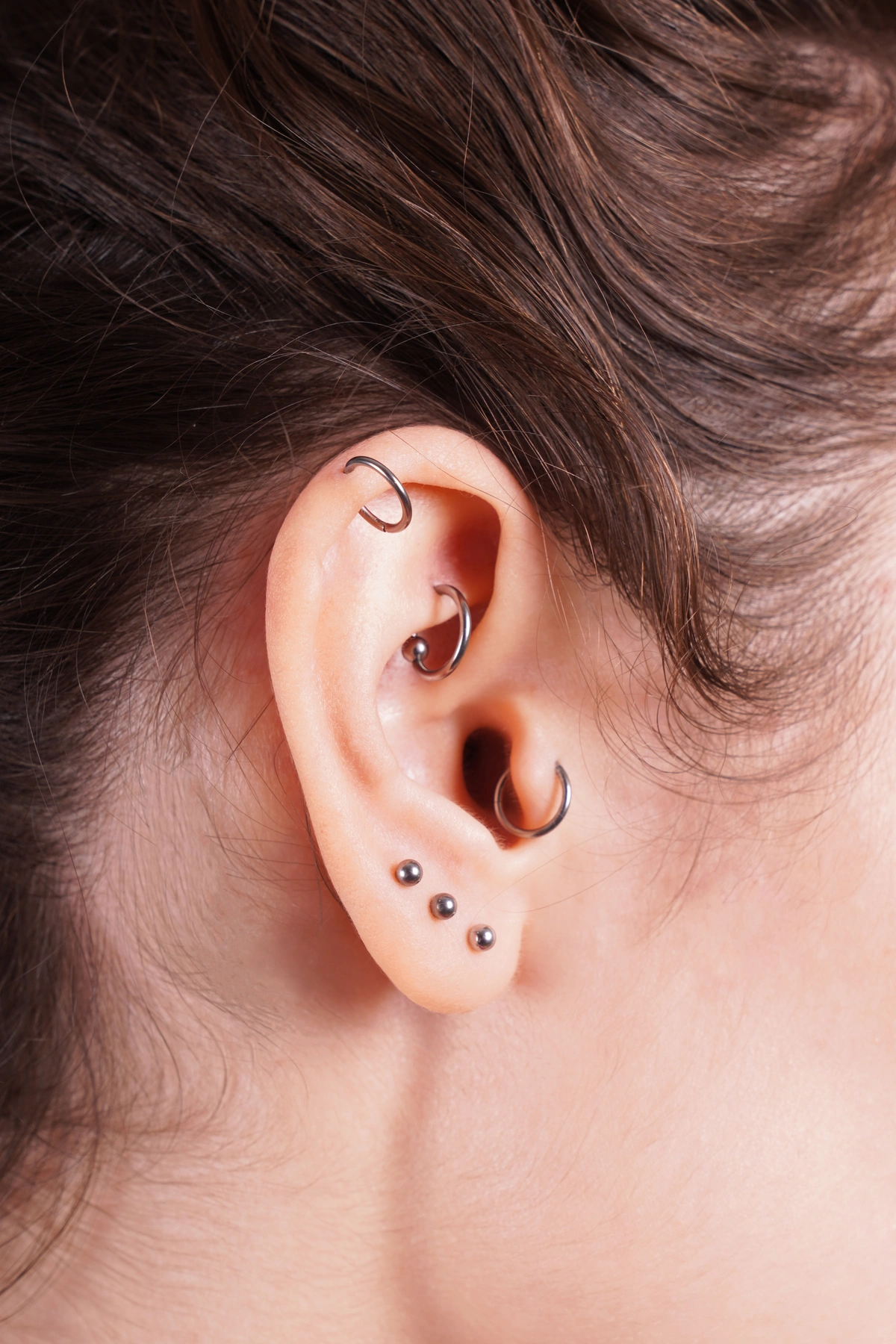 close up of ear with multiple cartilage and ear piercings