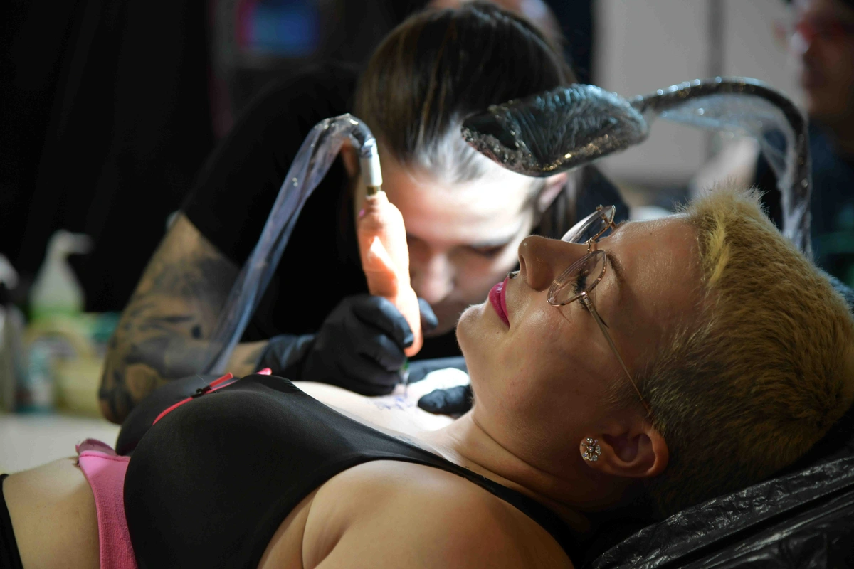 girl getting a tattoo on her right shoulder