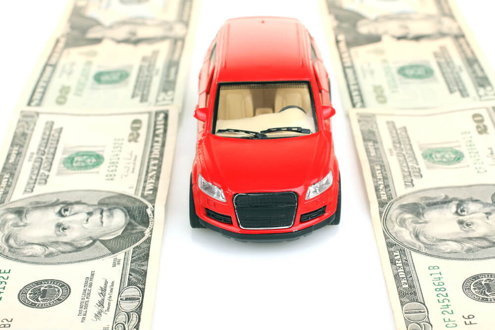 Red toy car on money road signifying title loan cash