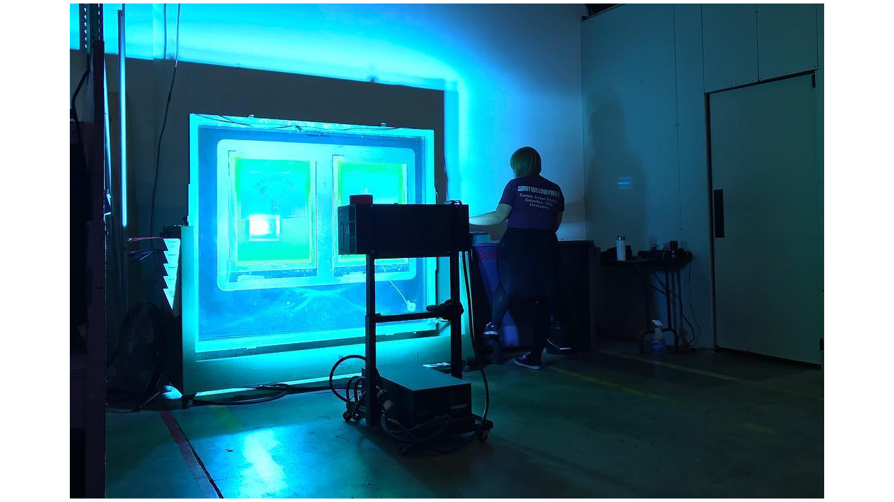 A woman exposing screens at a screen printing shop.