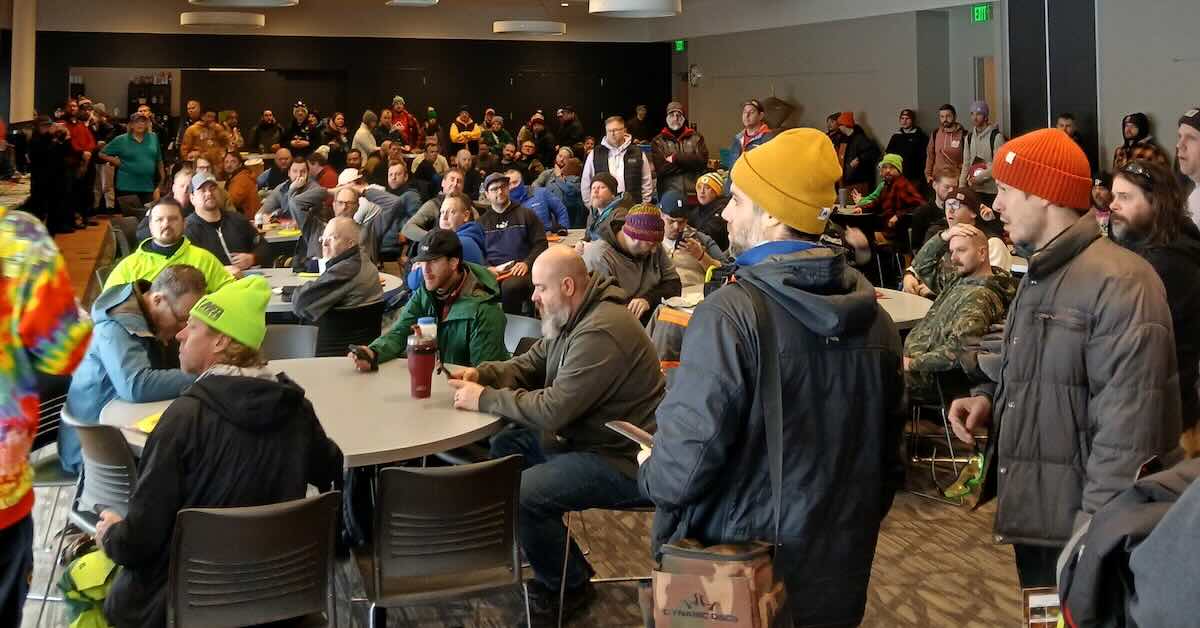 A large group of people in a room with tables and chairs