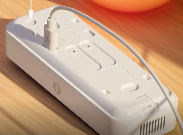 A white rectangular device with a wireDescription automatically generated