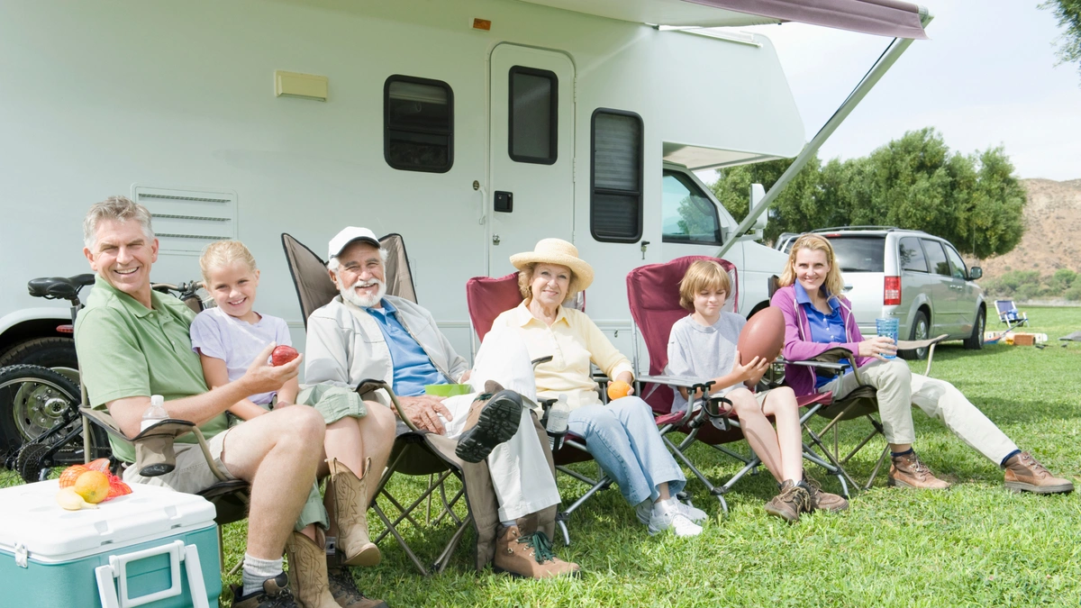 People smiling and sitting outside of an RV