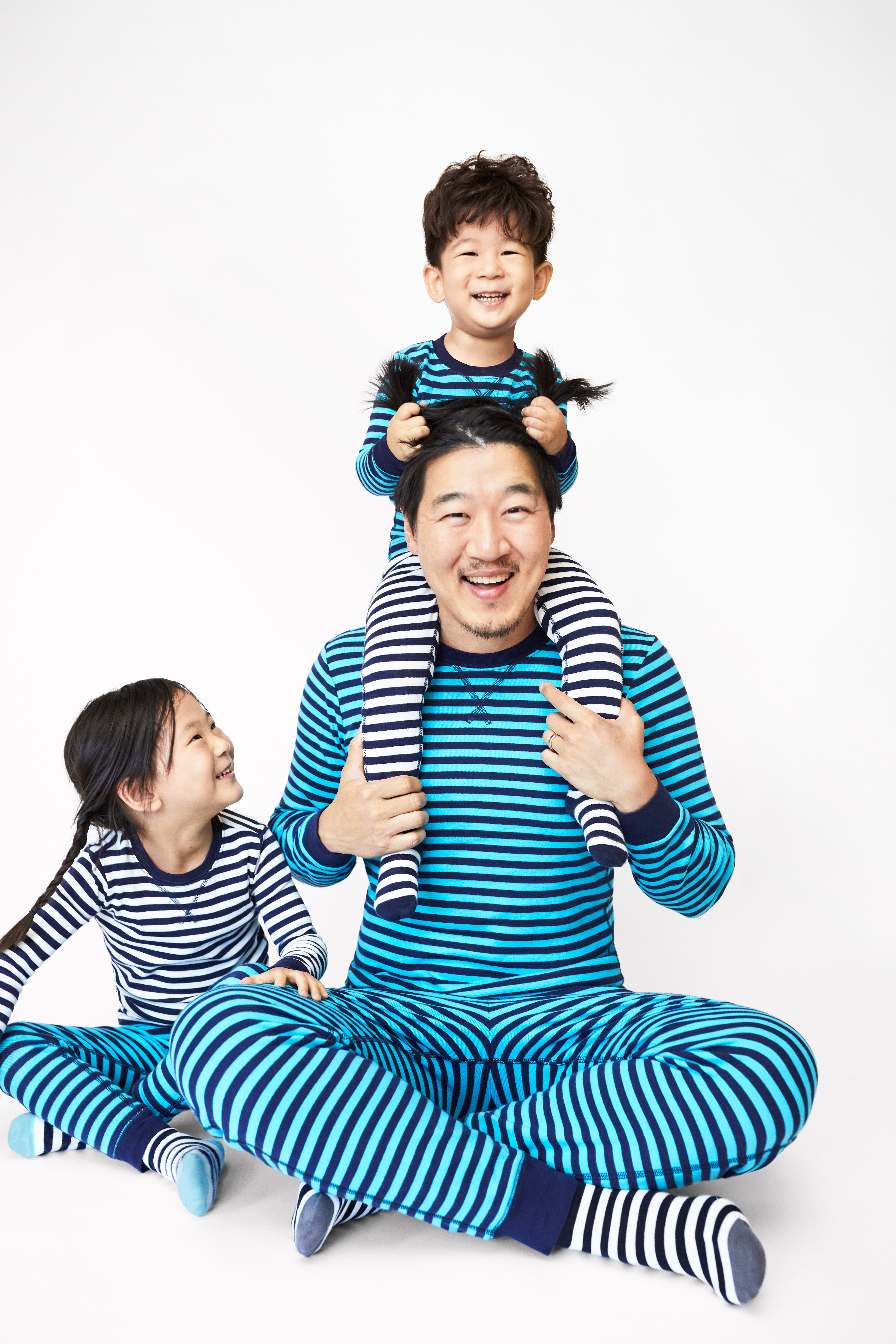 Dad and two kids sitting wearing striped blue pajamas