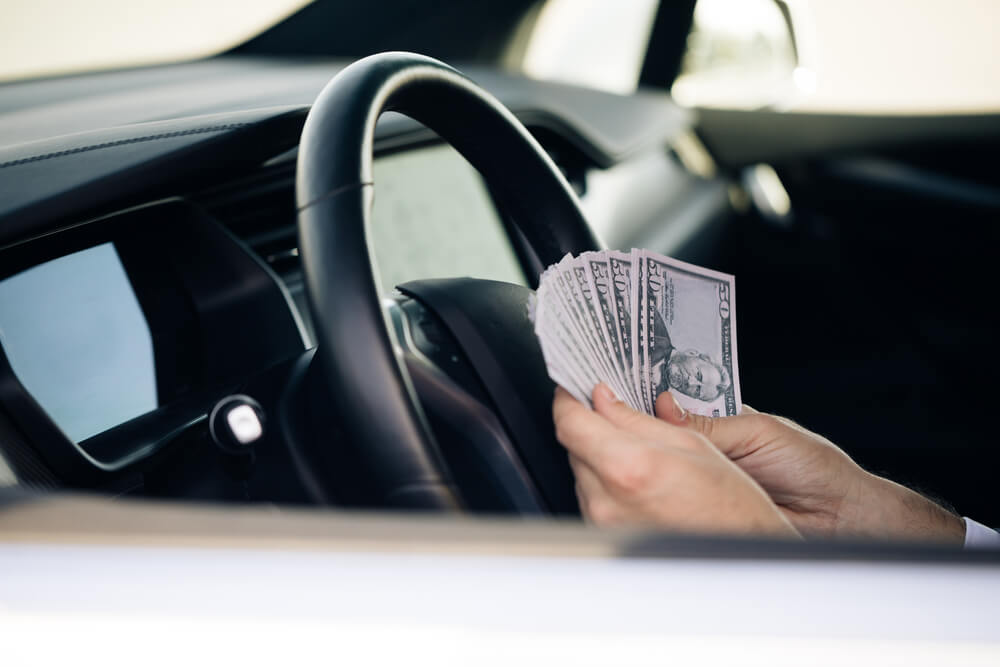 person sitting in car counting their vehicle title loan cash 