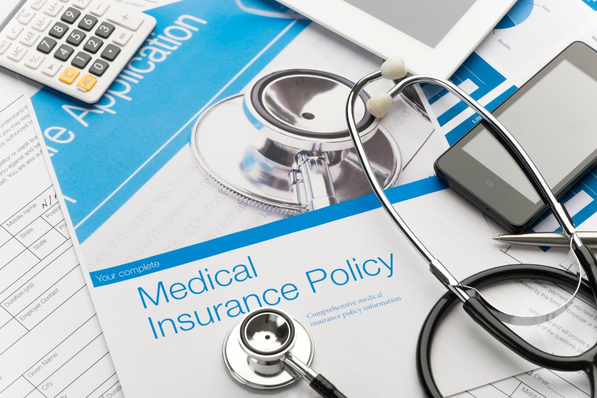 medicare and employer health insurance forms under a stethoscope