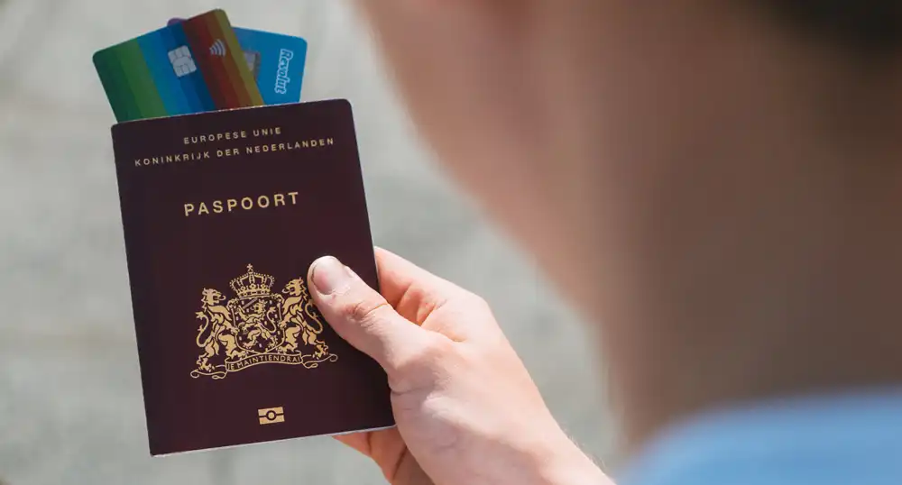 Man holding passport with credit cards sticking out top.