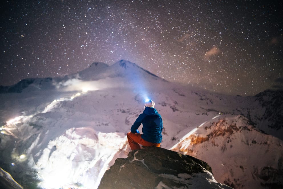 man sitting on mountain watching stars in the winter