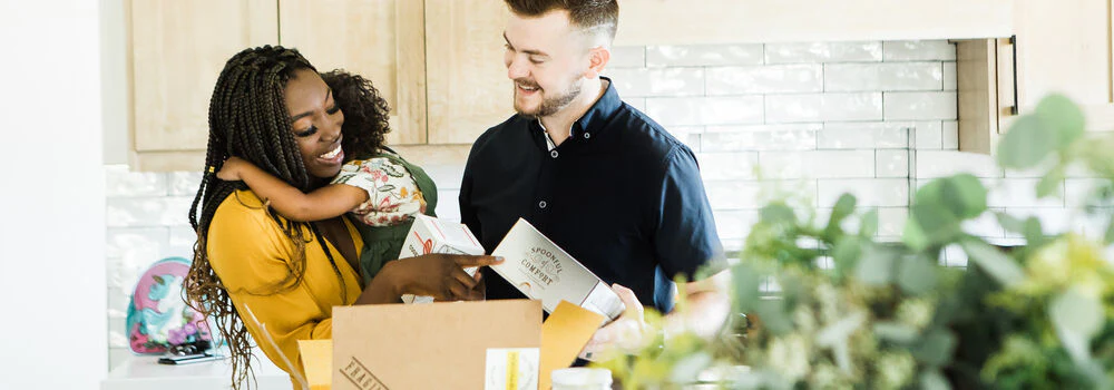 A family in a kitchen unboxing a care package