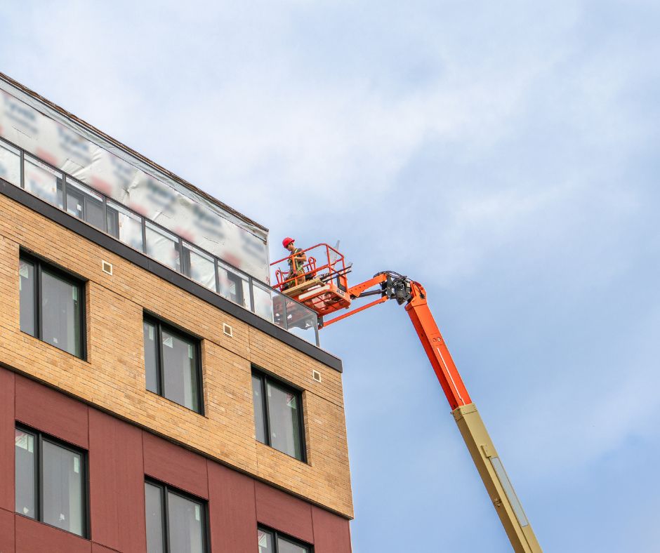 Man on a boom lift at max height working on a roof job