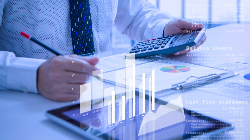 Man typing on keyboard while holding a calculator with graph icons