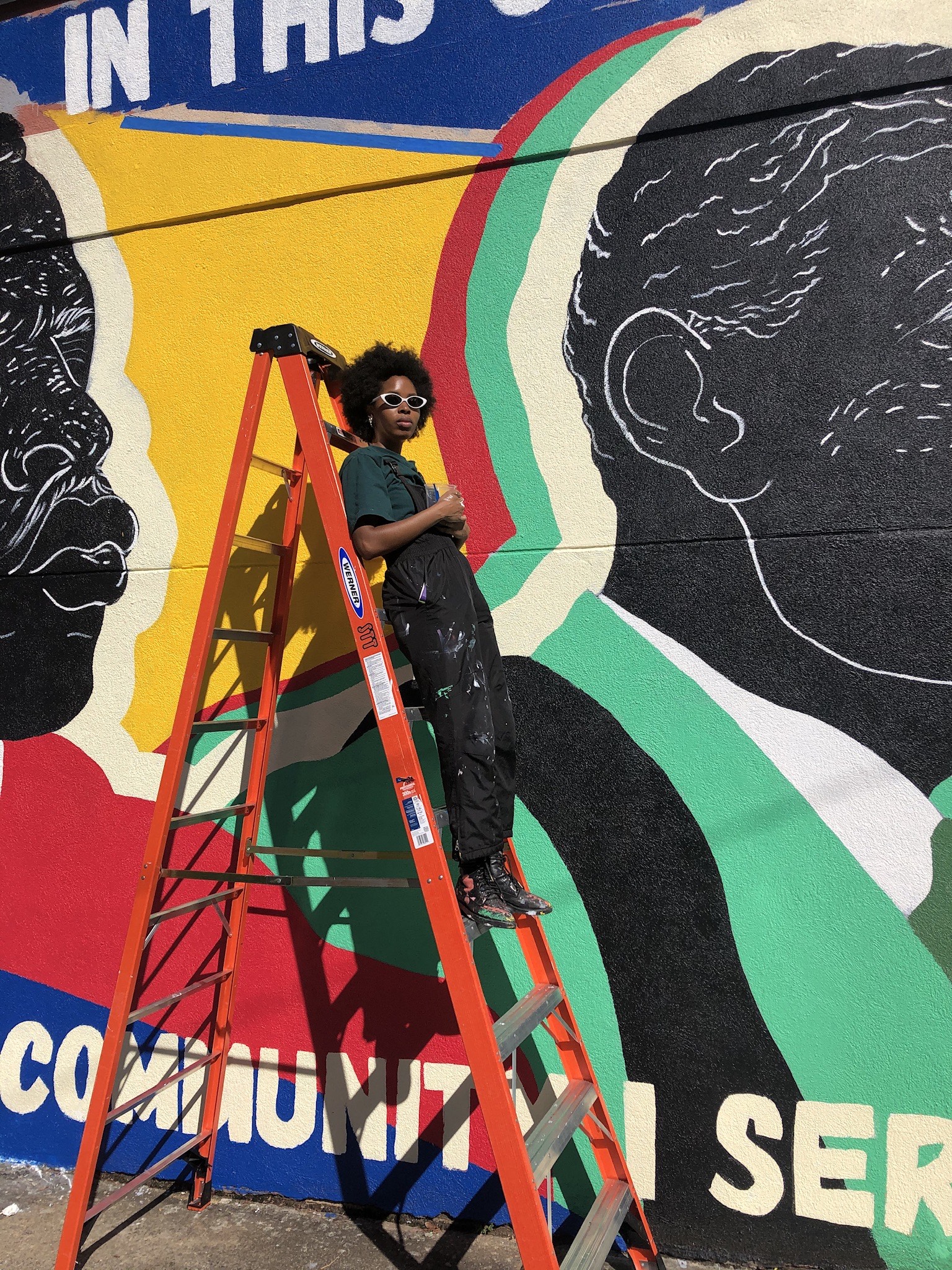artist neka king on ladder in front of mural