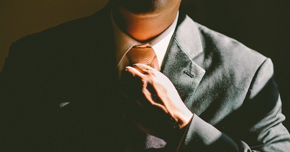 close-up photo of a man straightening a necktie