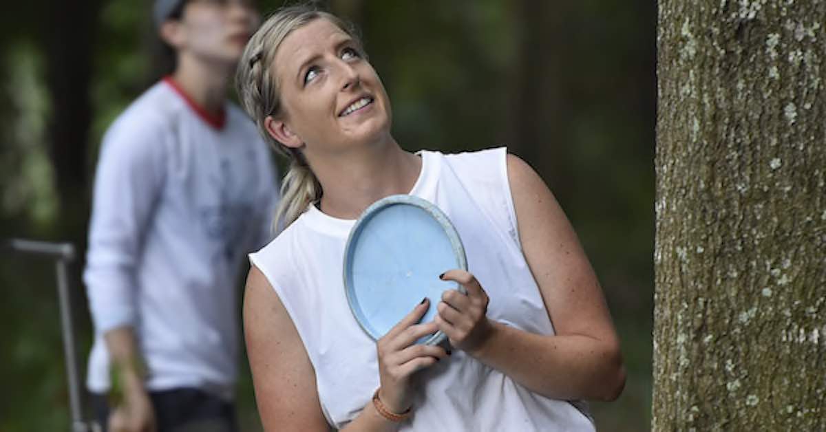A woman considering her next disc golf throw