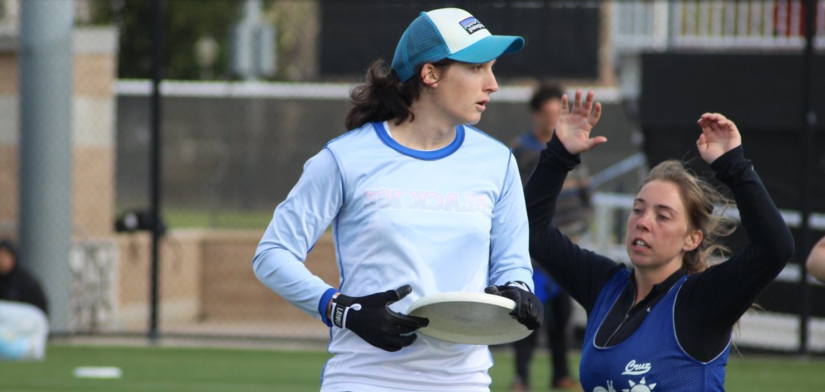 A woman with a frisbee is defended by another woman.