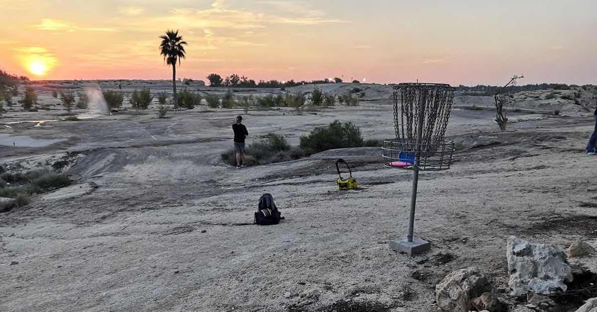 Disc golf basket in a desert landscape at sunset