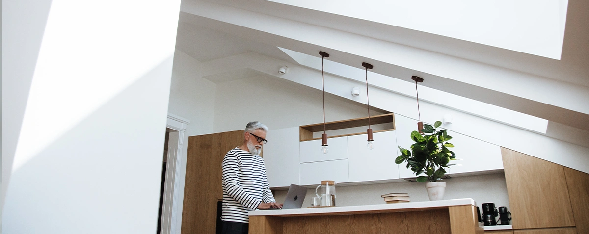 A person in their kitchen browsing the internet on a laptop