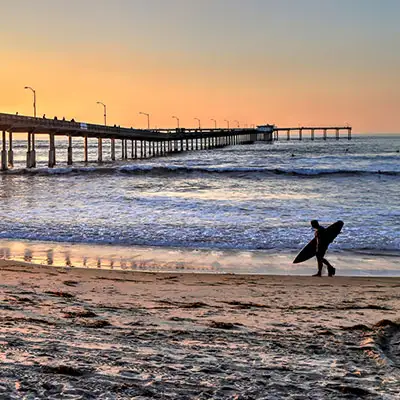 Man with surfboard walking on the beach.