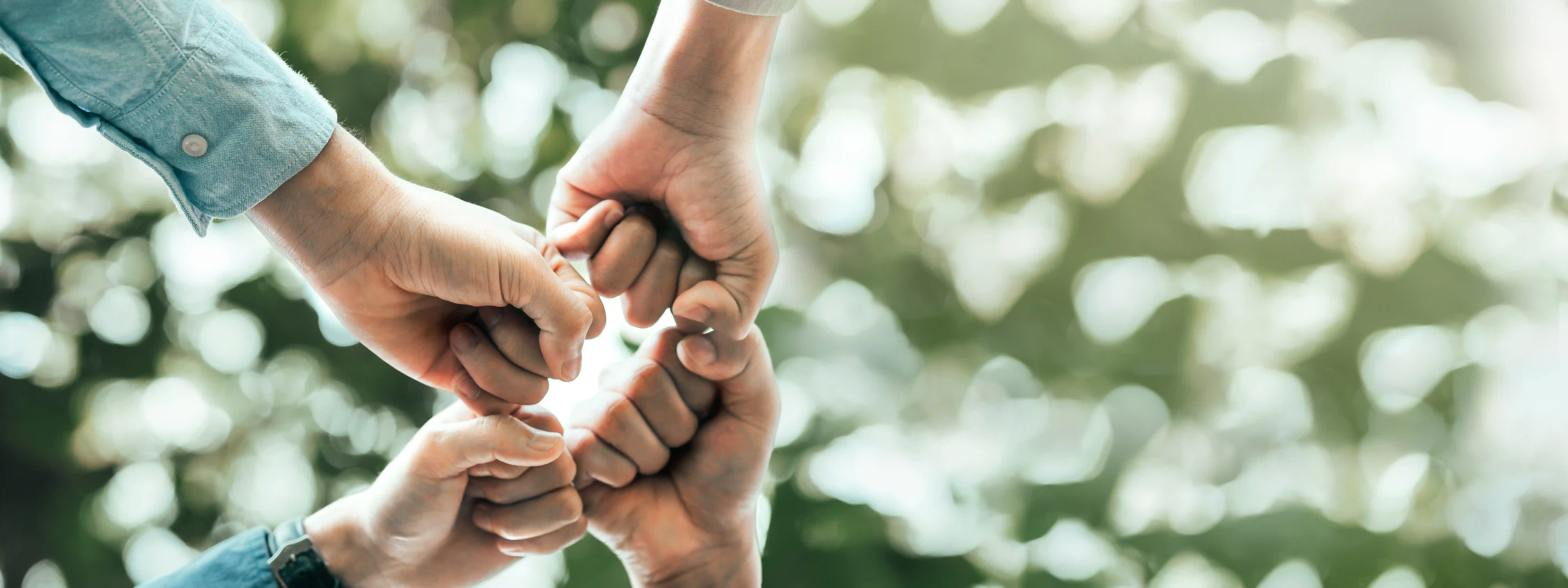 Diverse hands in group fist bump representing global teamwork and community impact through ethical recruitment