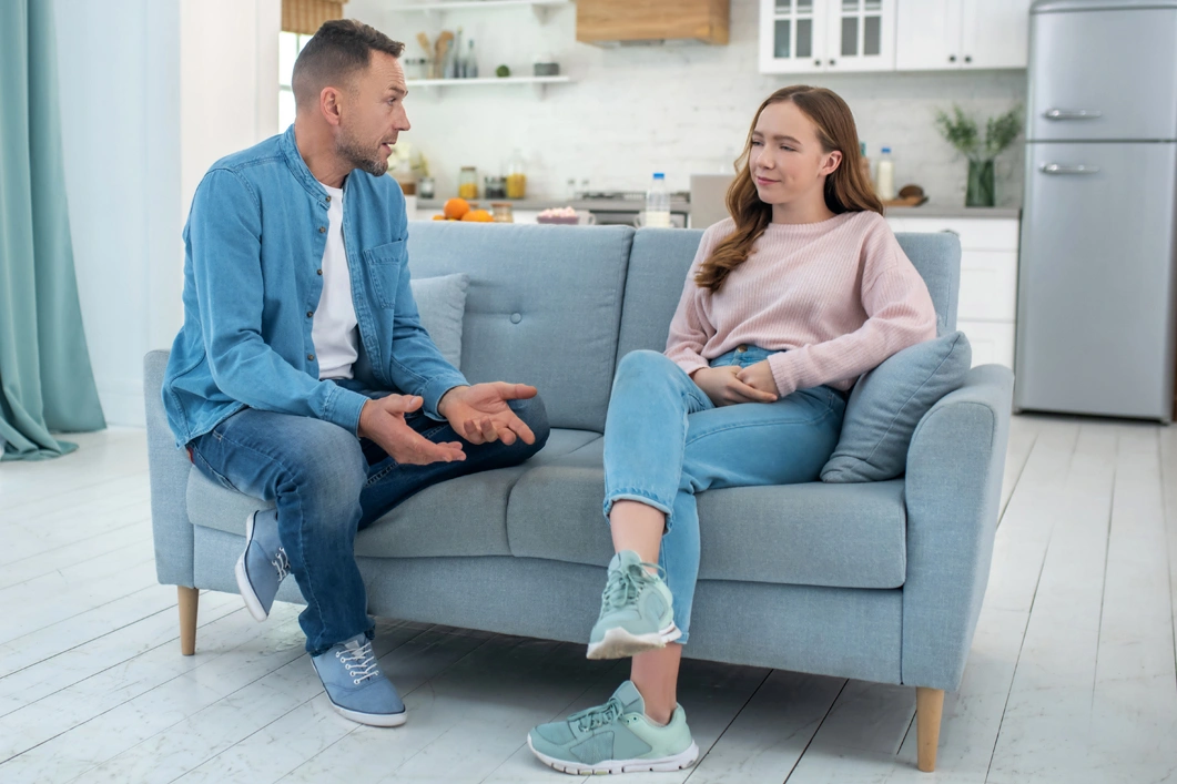 A father talking to his daughter on the couch