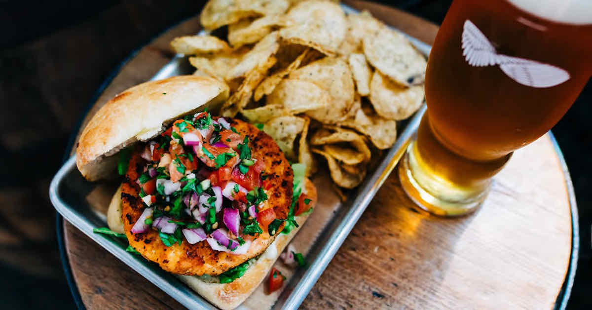 A well-played veggie burger with kettle chips and a beer as seen from above
