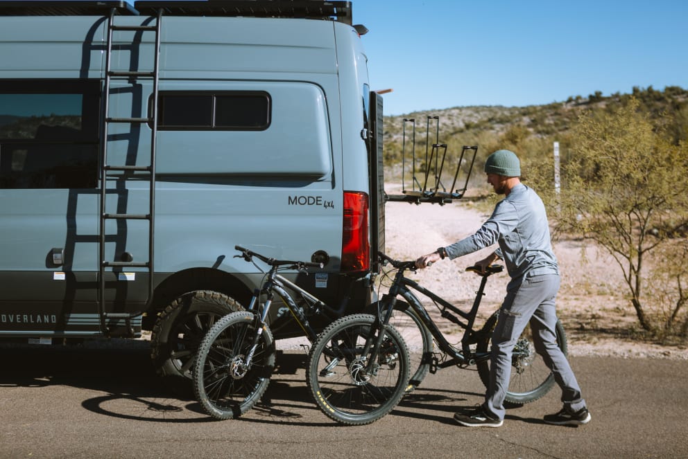 man unloads bike from storyteller overland
