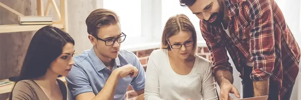 A group of people gathered around a laptop.