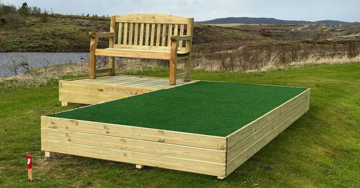 Raised wood-framed turf tee pad with wooden bench attachment