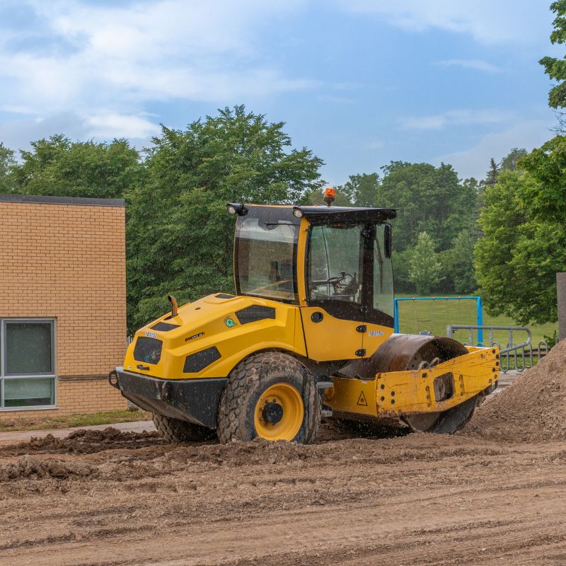 Smooth drum roller compacting dirt on a construction site