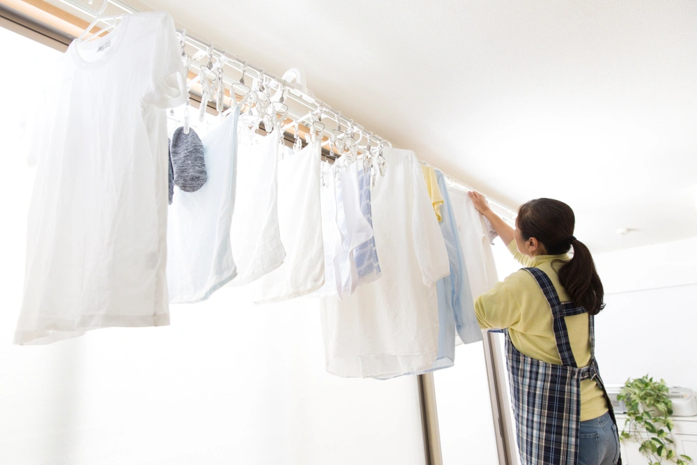 woman hanging up clothes to dry on curtain rail
