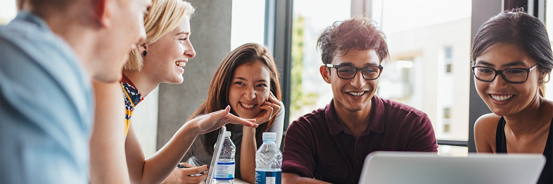 A group of people laughing at the laptop.