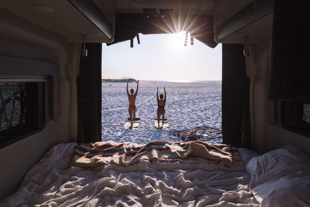 friends doing yoga on the beach outside of campervan