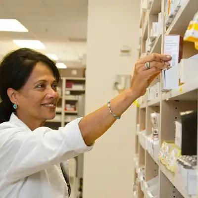 Pharmacist puts medication on a shelf.