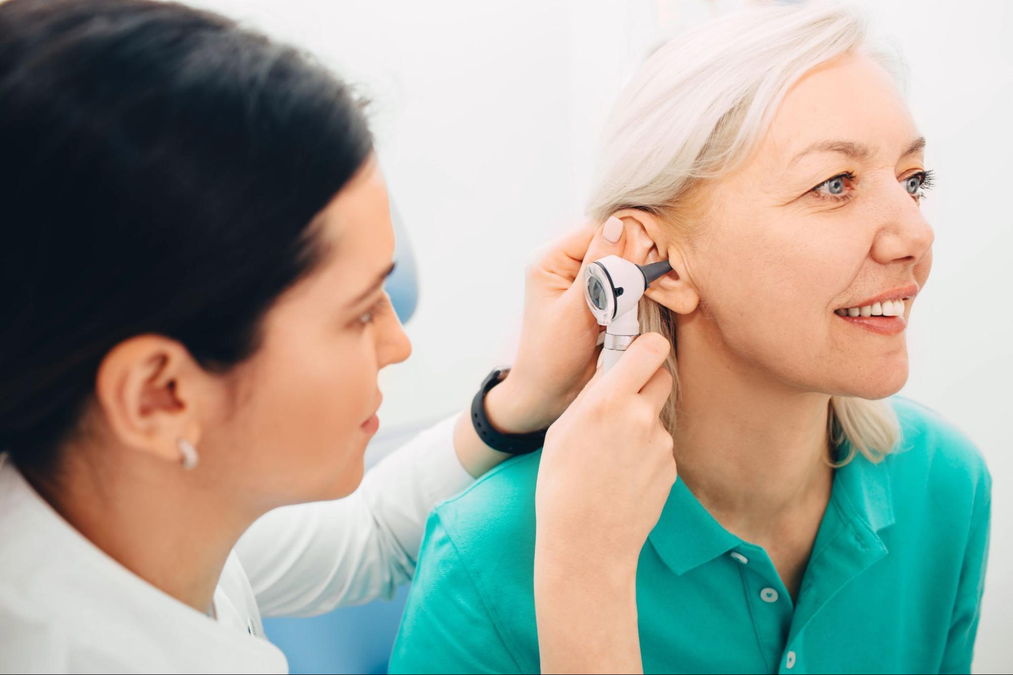 doctor examining the ear of an old woman