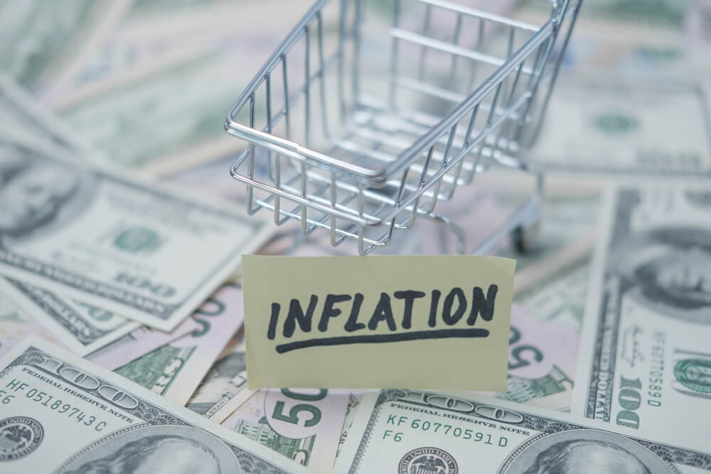 miniture shopping cart on money with paper sign with text inflation