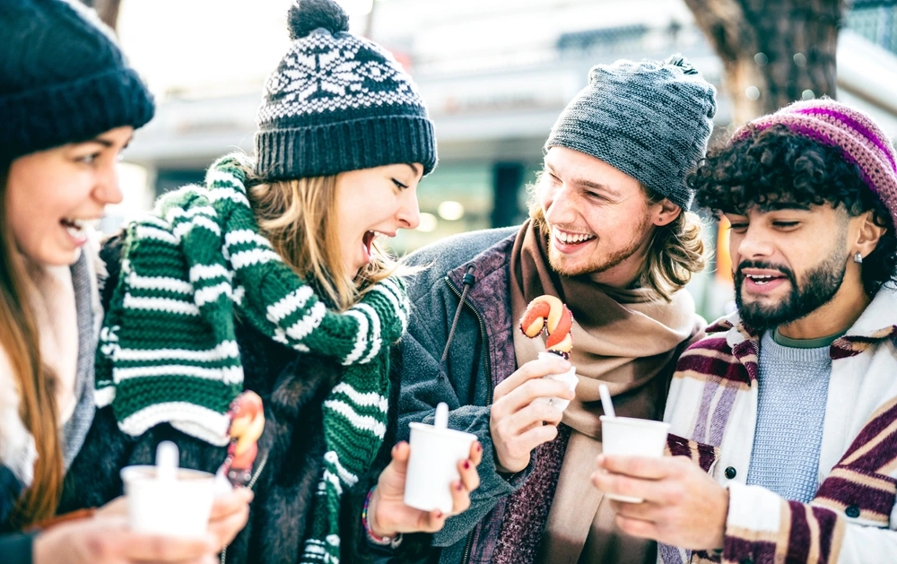Group of friends talking and drinking coffee outdoors during winter