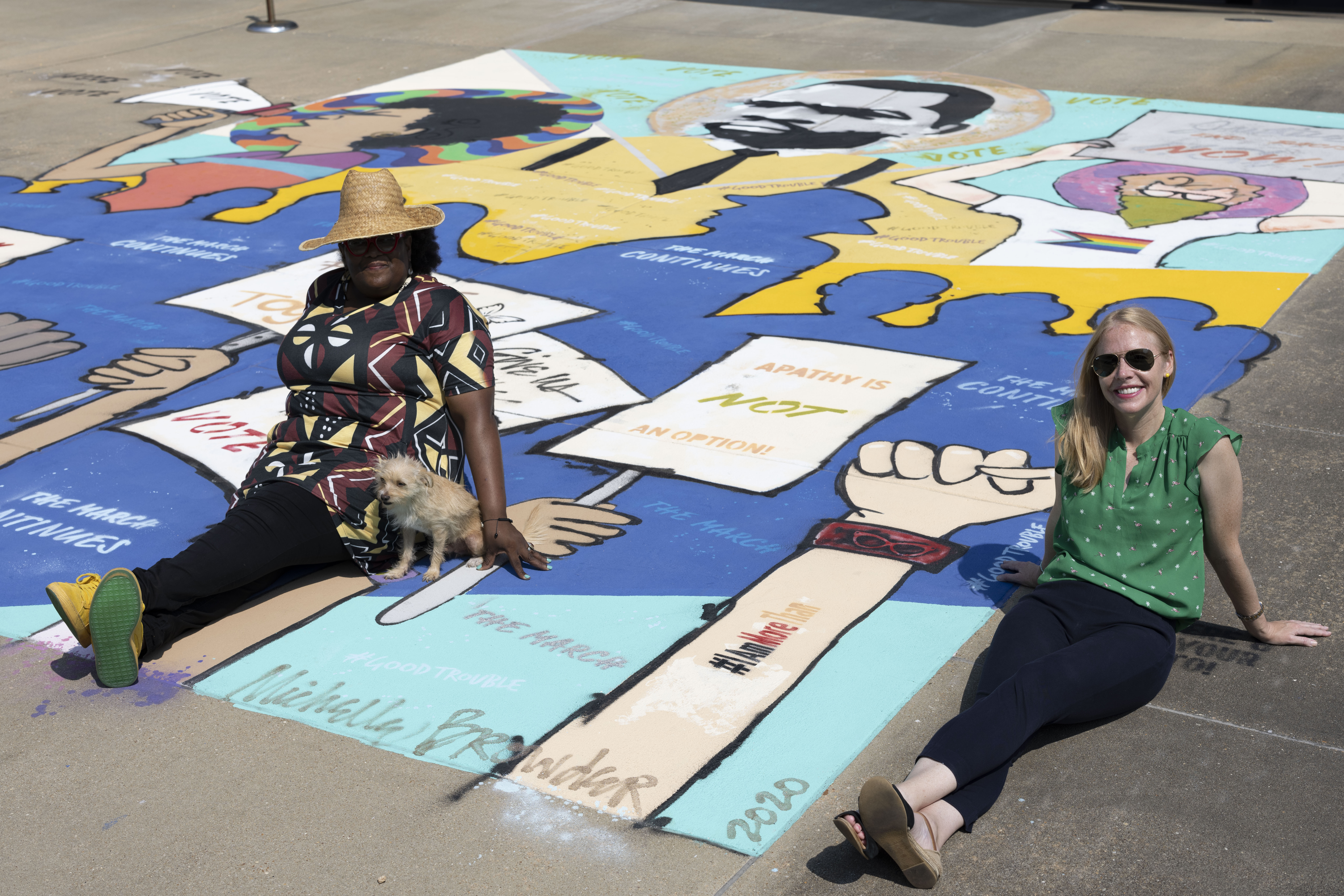 People sitting on an outdoor mural and smiling