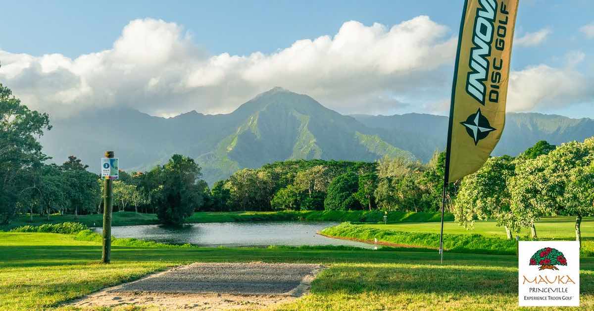 Golf course landscape with misty mountains in distance and water in foreground