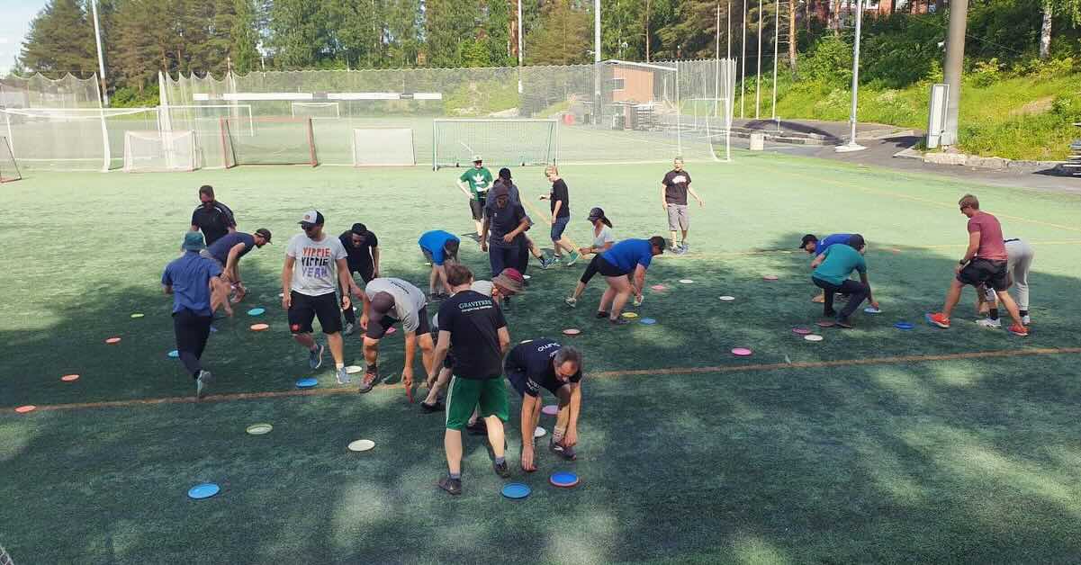 A group on a turf field playing a game with discs on the ground