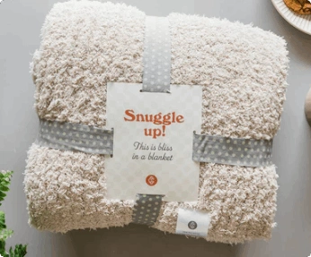 A cozy comfort throw is bundled with a label that says "Snuggle up!"