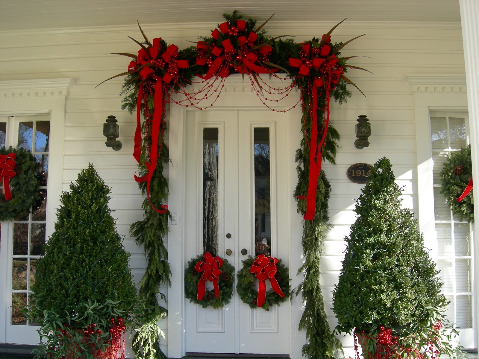 Christmas decorations around a door on a white house