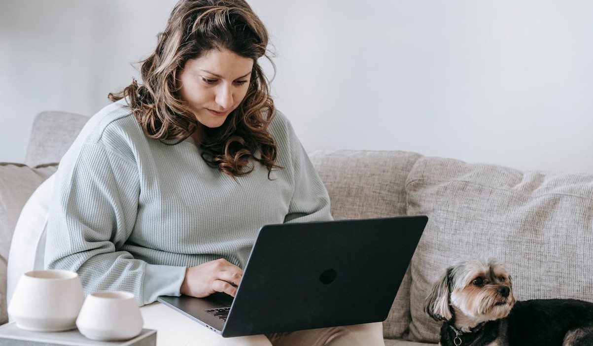 Woman researching broadband switching options while relaxing on her sofa with a dog