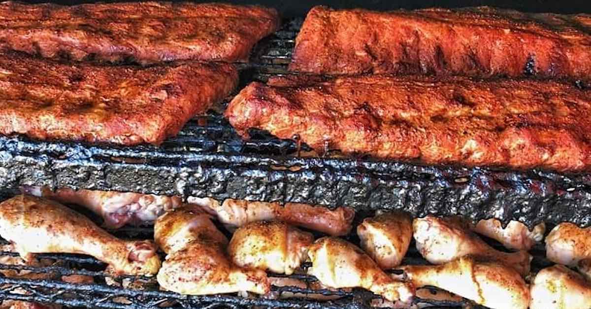Ribs and chicken legs cooking in a large grill